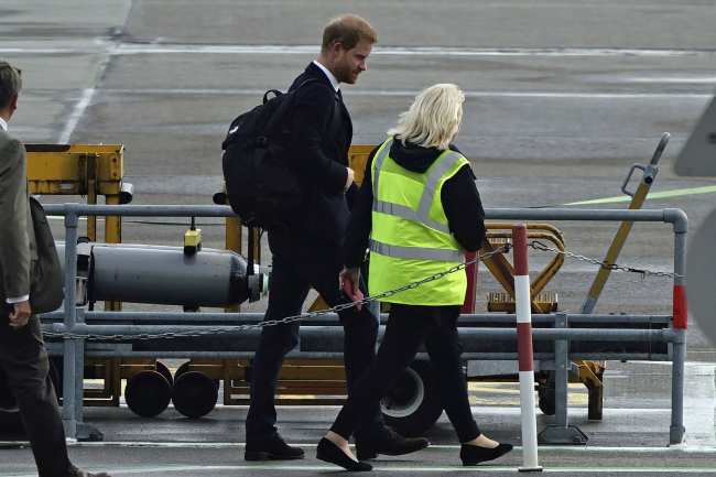 El principe Harry de Gran Bretana a la izquierda camina sobre la pista antes de abordar un avion a Londres tras la muerte de la reina Isabel II