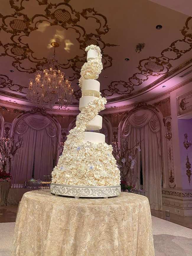              El pastel de bodas tenia una altura de ocho pisos y estaba adornado con flores blancas            