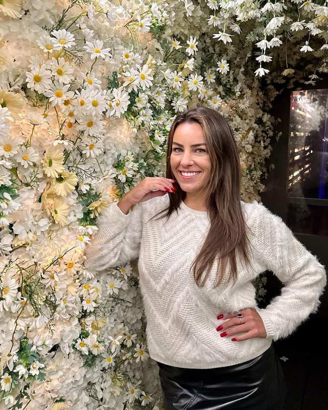 Veronica Rodriguez de pie junto a un muro de flores