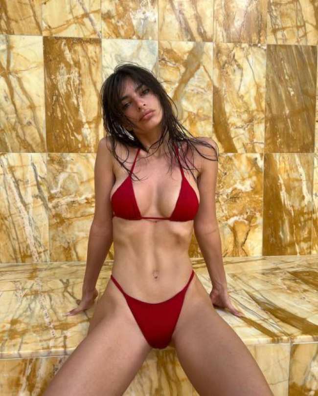 Emily Ratajkowski sentada en bikini rojo