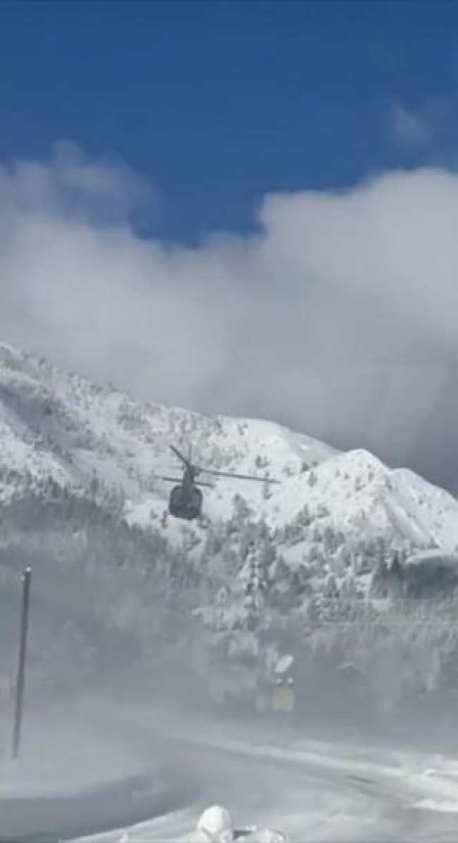 Un helicoptero sobrevolando montanas nevadas