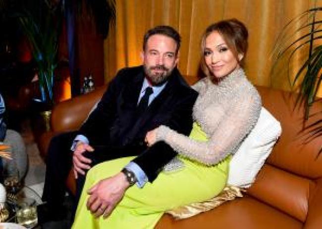 Ben Affleck y Jennifer Lopez sentados juntos en un sofa