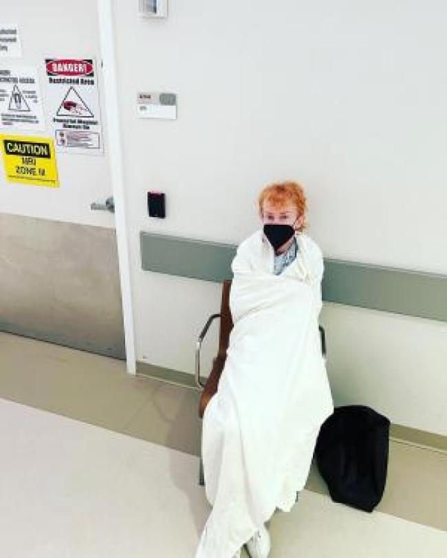 Kathy Griffin envuelta en una manta y sentada en una silla en un hospital
