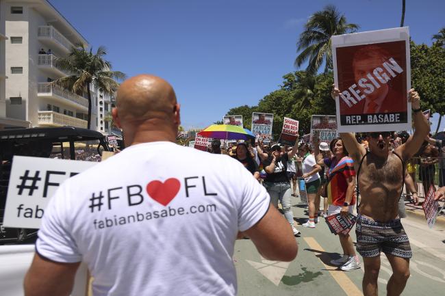 Un manifestante sostiene un cartel que pide la renuncia del representante Fabian Basabe mientras empresas organizaciones municipales locales y LGBTQ desfilan hacia el norte en Ocean Drive en el desfile del Orgullo a la luz de los proyectos de ley antiLGBTQ en la legislatura de Florida el 16 de abril 2023 en Miami Beach Florida