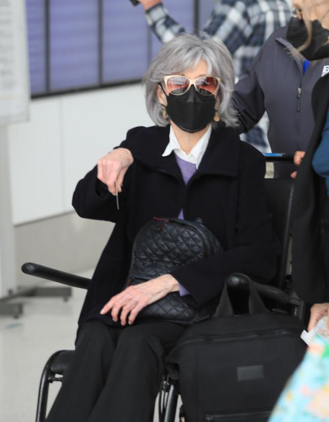 Jane Fonda es empujada en silla de ruedas por el aeropuerto.
