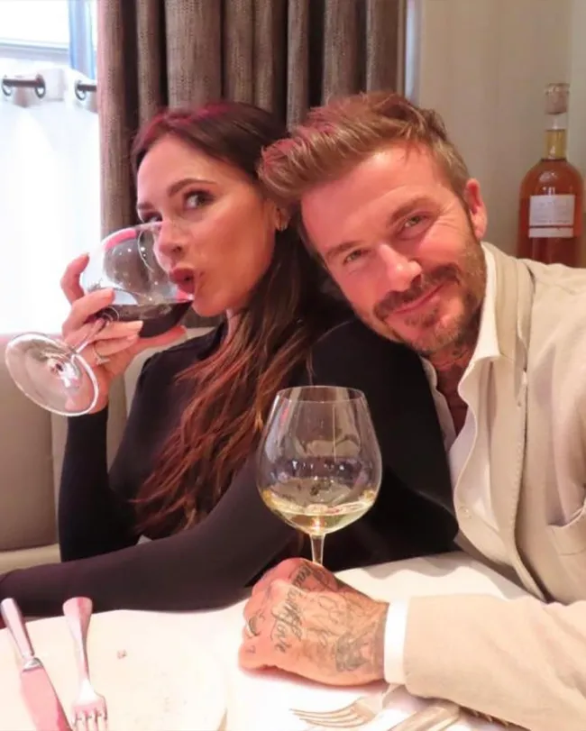 Victoria Beckham bebiendo vino mientras posa para una foto con David Beckham.