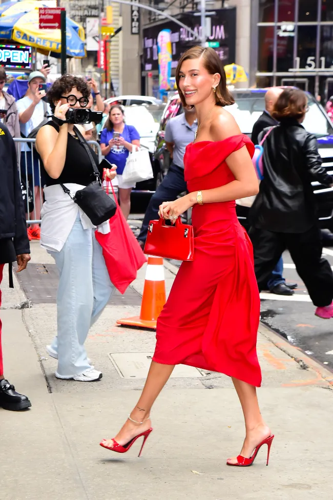 Hailey Bieber comenzó su día con un vestido midi rojo de Vivienne Westwood y accesorios a juego para su entrevista en “Good Morning America”.
