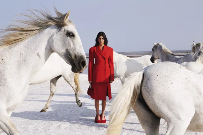 En una de las imágenes, Jenner, vestida de rojo, mira fijamente a la cámara mientras está rodeada de los elegantes equinos.