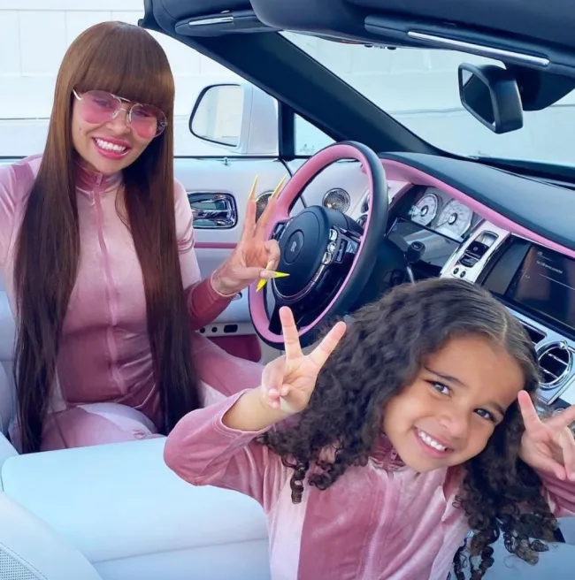 blac chyna y dream kardashian a juego con sudaderas rosas sosteniendo los dedos con el signo de la paz