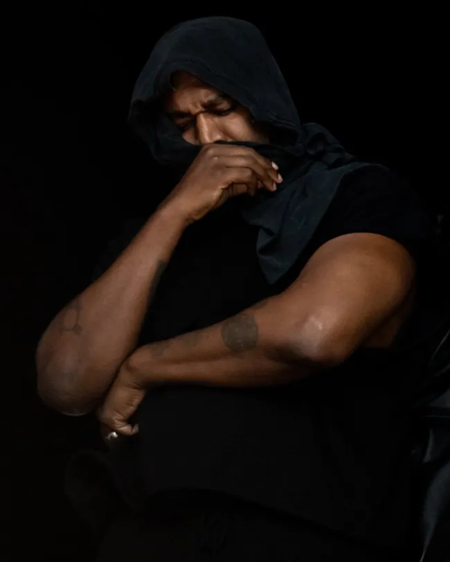 Kanye West se cubre la mitad de la cara con un pañuelo en la cabeza y parece triste en su mano.