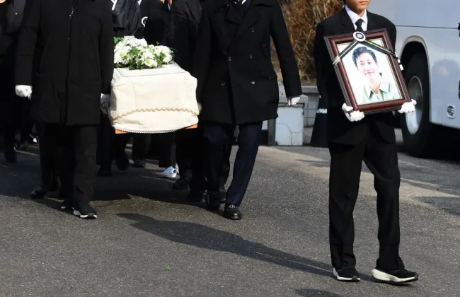 El hijo de Lee Sun-kyun llevando su retrato frente a un ataúd