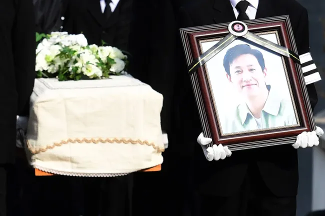 El hijo de Lee Sun-kyun llevando su retrato frente a un ataúd