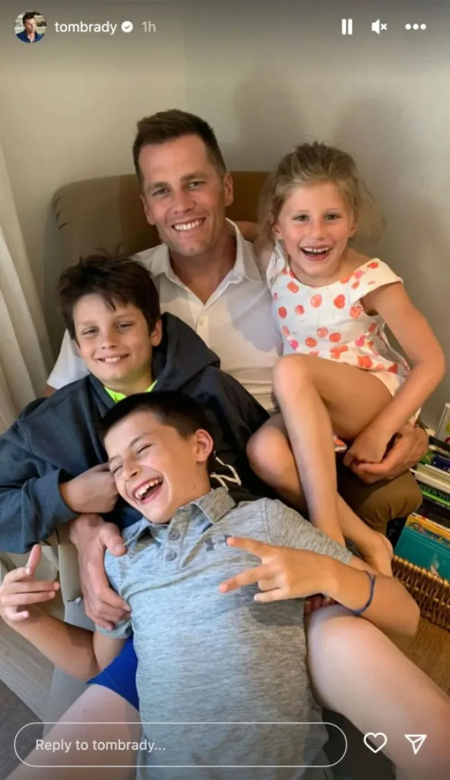 Tom Brady con sus tres hijos en su regazo.