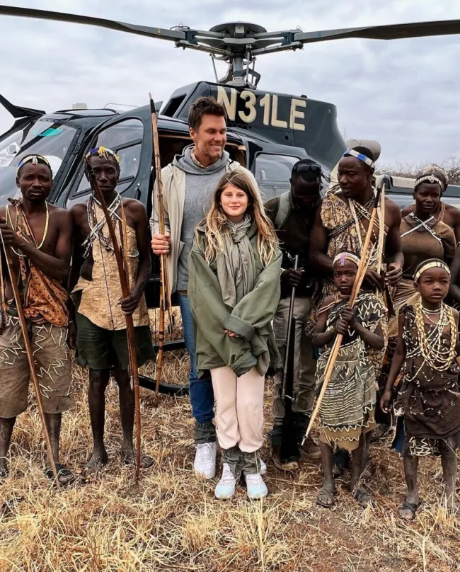 Tom Brady y su hija parados frente a un helicóptero con tribus de personas