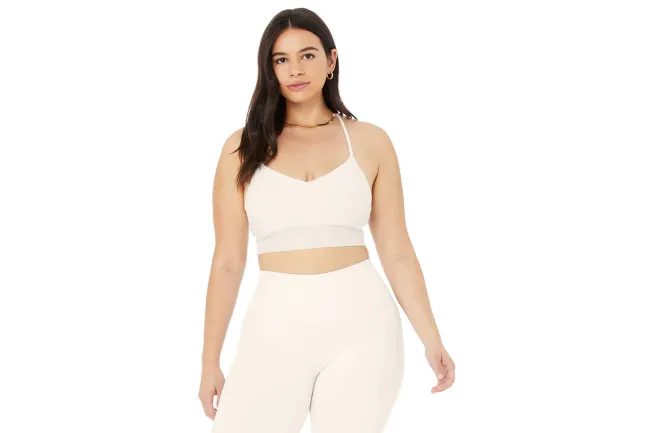 Una modelo con un sujetador y leggings blancos de Alo Yoga.