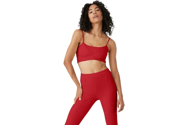 Una modelo con sujetador deportivo rojo y leggings.