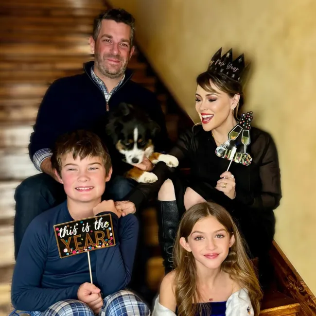 Alyssa Milano, Dave Bugliari y sus dos hijos sentados en las escaleras con su perro