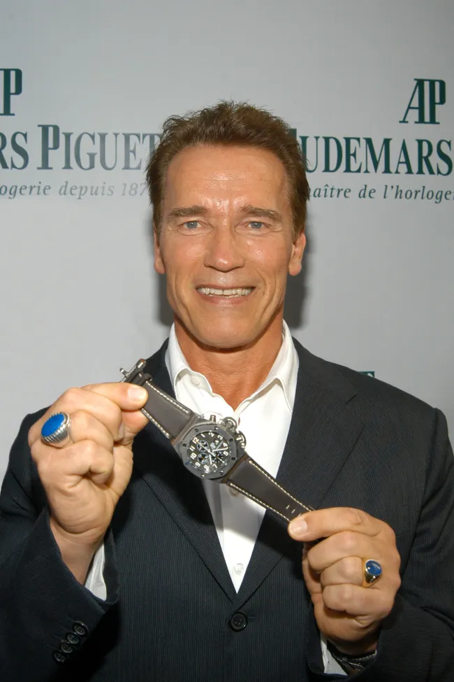 Arnold Schwarzenegger sosteniendo un reloj.