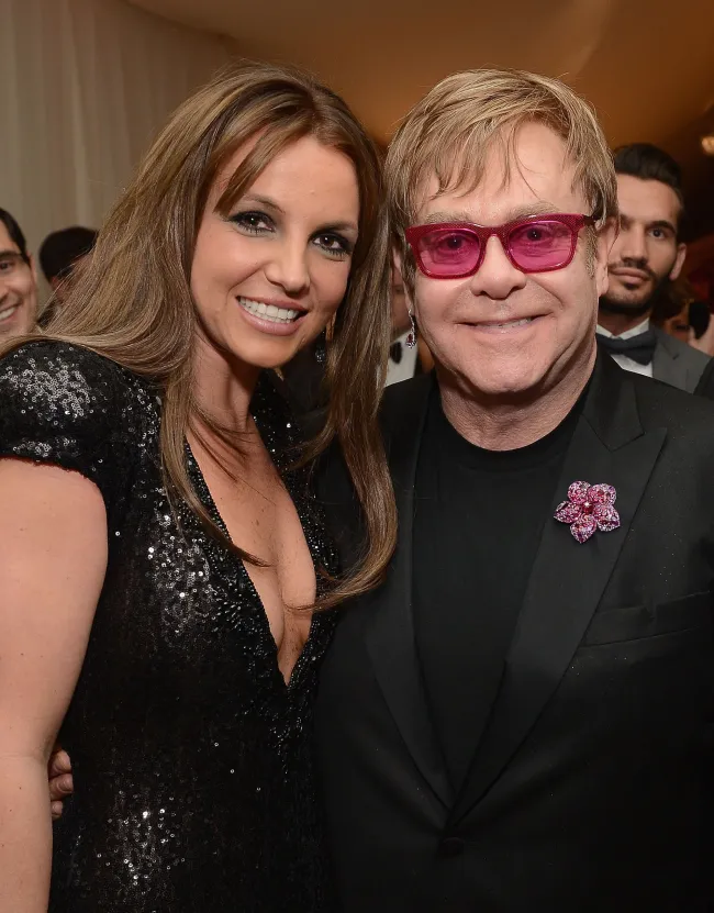 Britney Spears y Elton John posando juntos en un evento.