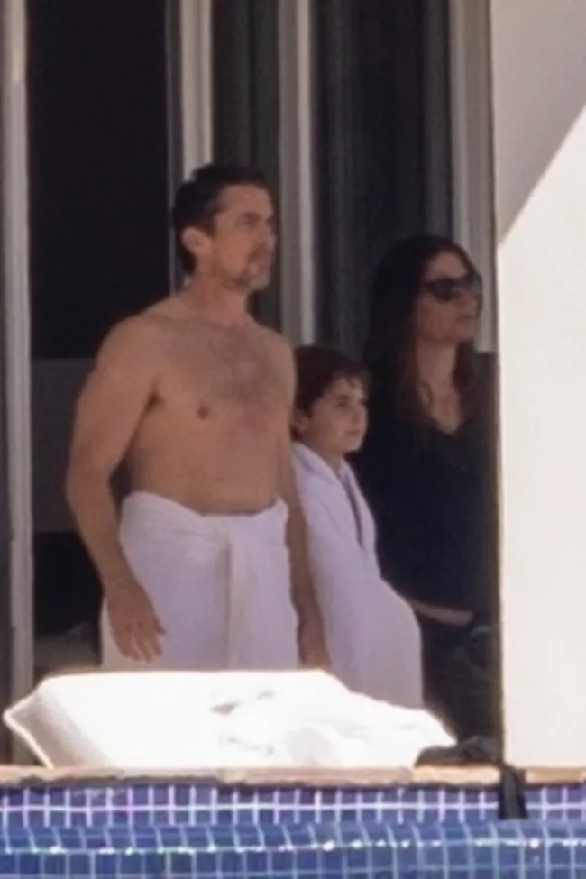 Christian Bale con una toalla en la cintura junto a su hijo