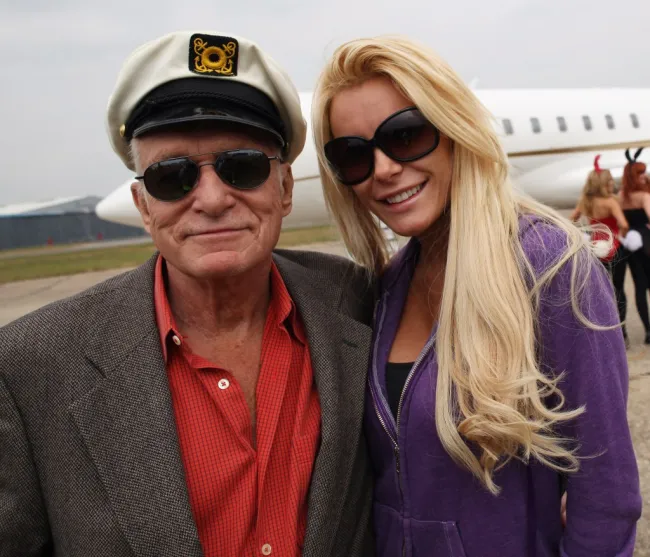 Hugh Hefner y Crystal parados frente a un avión