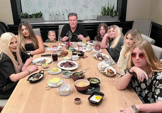 Dean McDermott sentado en una mesa con sus hijos y Tori Spelling.