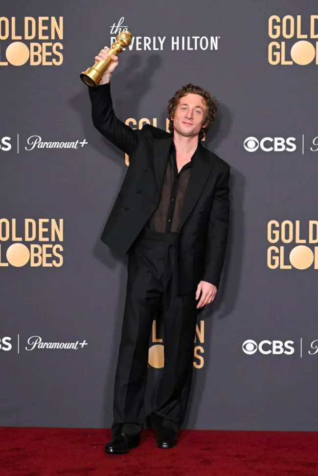 Jeremy Allen White en la alfombra roja, sosteniendo en alto su trofeo de los Globos de Oro