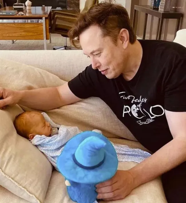 Elon Musk mirando a su bebé en un sofá.