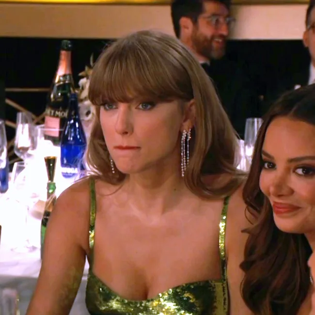 Taylor Swift con aspecto enojado sentada junto a Keleigh Sperry
