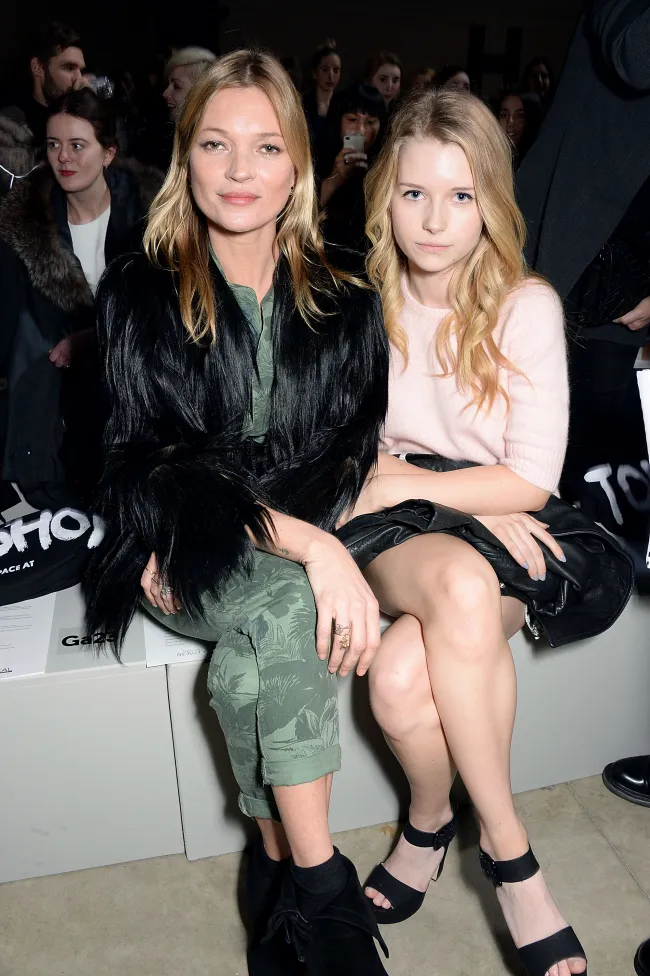 Kate Moss y Lottie Moss sentadas juntas en un desfile de moda.