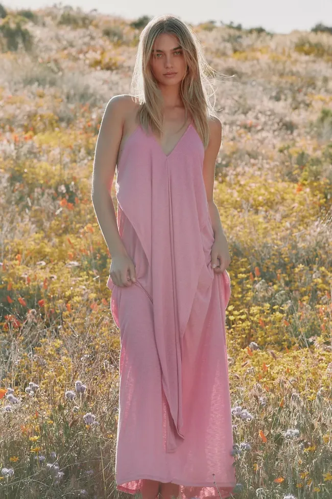Una modelo en un campo con un vestido largo rosa.