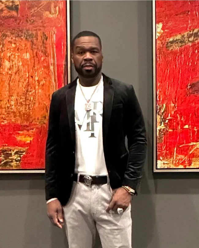 50 Cent con una chaqueta de terciopelo y una camiseta blanca.