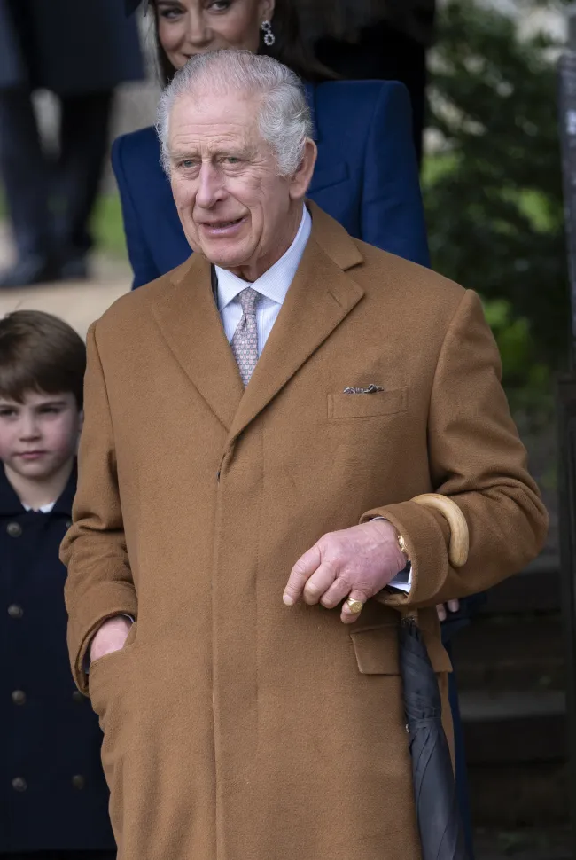 El rey Carlos con un abrigo marrón.