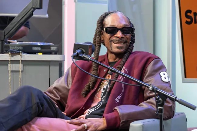 Snoop Dogg sentado en una silla con un micrófono.