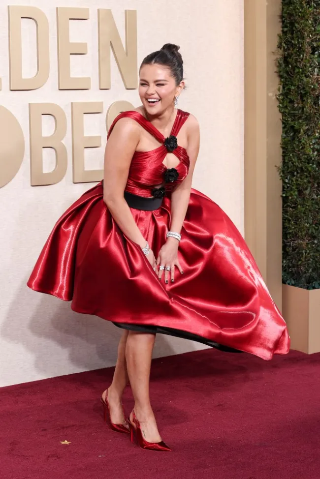 selena gomez sonriendo y sosteniendo su vestido en la alfombra roja de los globos de oro 2024