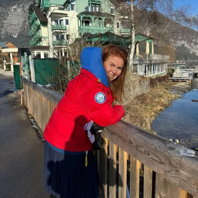 sarah ferguson de pie sobre un puente de madera con vistas a las montañas y a un pequeño pueblo