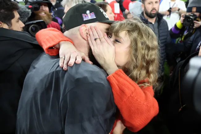 Taylor Swift besando a Travis Kelce en el campo de fútbol.