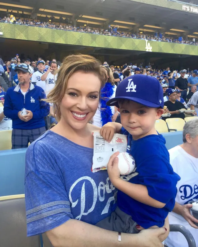 Alyssa Milano posa con su hijo en un partido de béisbol.
