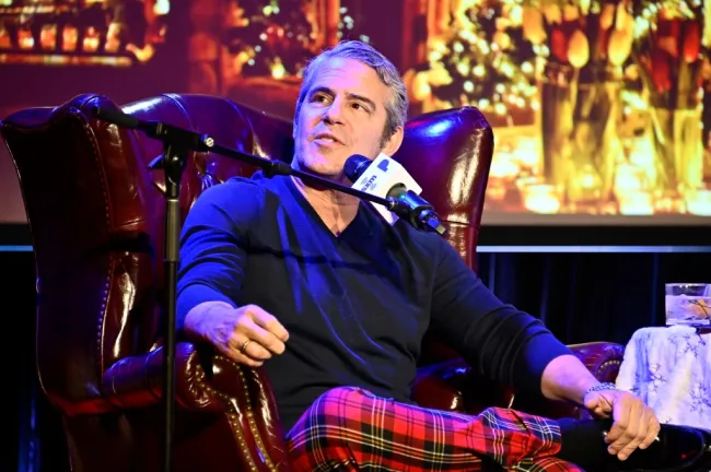 Andy Cohen sentado en una silla de cuero con un micrófono en la cara.