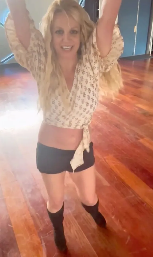 Britney Spears bailando con los brazos en alto.