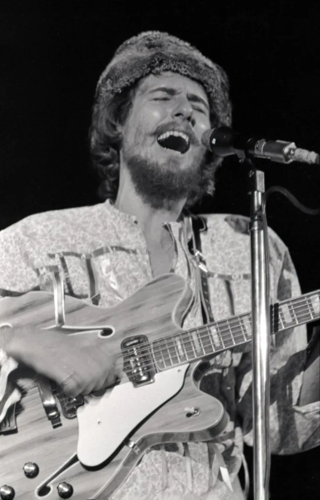 John Phillips cantando y tocando la guitarra.