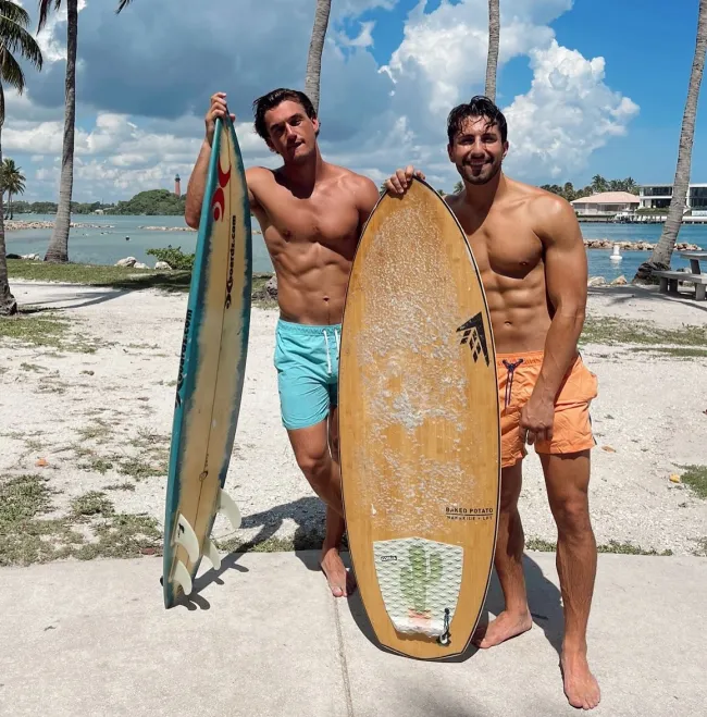 Jason Tartick y Tyler Cameron sin camisa en la playa.