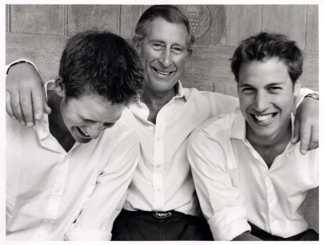 El rey Carlos sonríe abrazando a sus hijos, el príncipe William y el príncipe Harry.