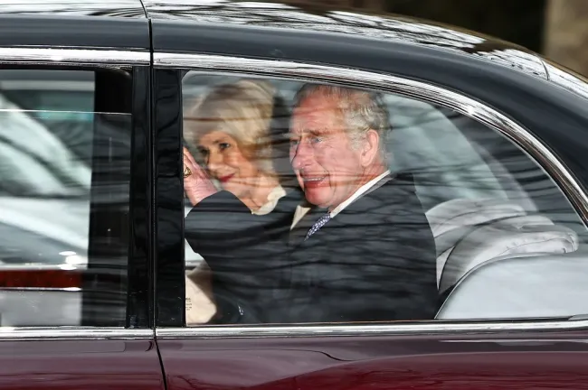 El rey Carlos y la reina Camilla saludan a la multitud desde su coche.