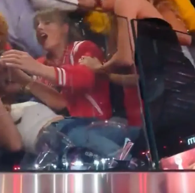 Taylor Swift inclinada sobre su amiga que se cayó.