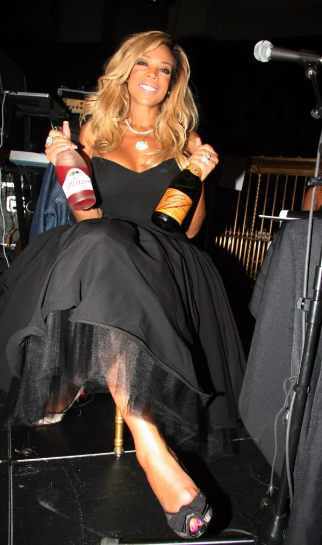 Wendy Williams sosteniendo dos botellas de alcohol.