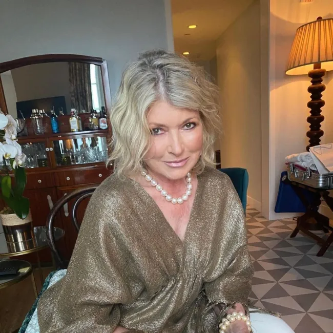 Martha Stewart sentada con un top dorado.