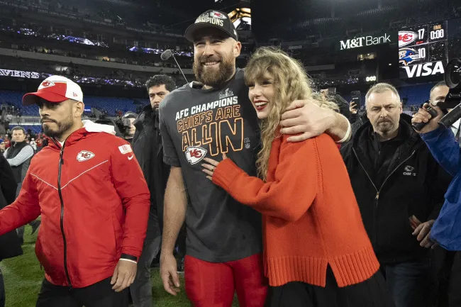 Taylor Swift abrazando a Travis Kelce en un campo de fútbol.