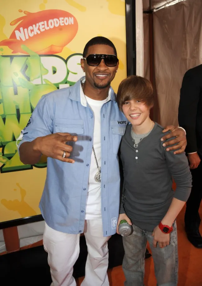 Usher con su brazo alrededor de los hombros de un joven Justin Bieber