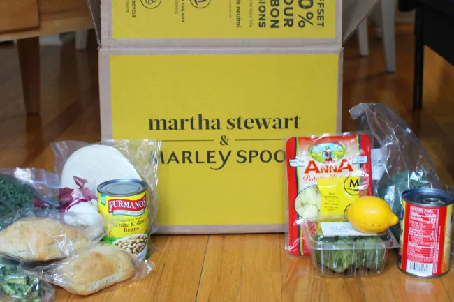 Una caja amarilla de Martha Stewart x Marley Spoon con los ingredientes colocados delante